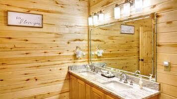 A wooden-paneled bathroom with a large mirror, two sinks, and a towel rack.