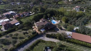 An aerial view of a residential area with a large house featuring a swimming pool, surrounded by greenery and other houses. - Villa Tresino apartments "Velia" (Alani)