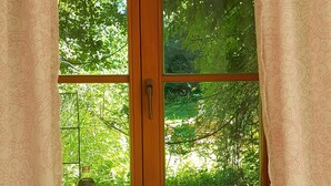 A room with a wooden door and window, a small table with a bottle and a glass, and a decorative item on the windowsill. - Martina's place (Rottenbuch)