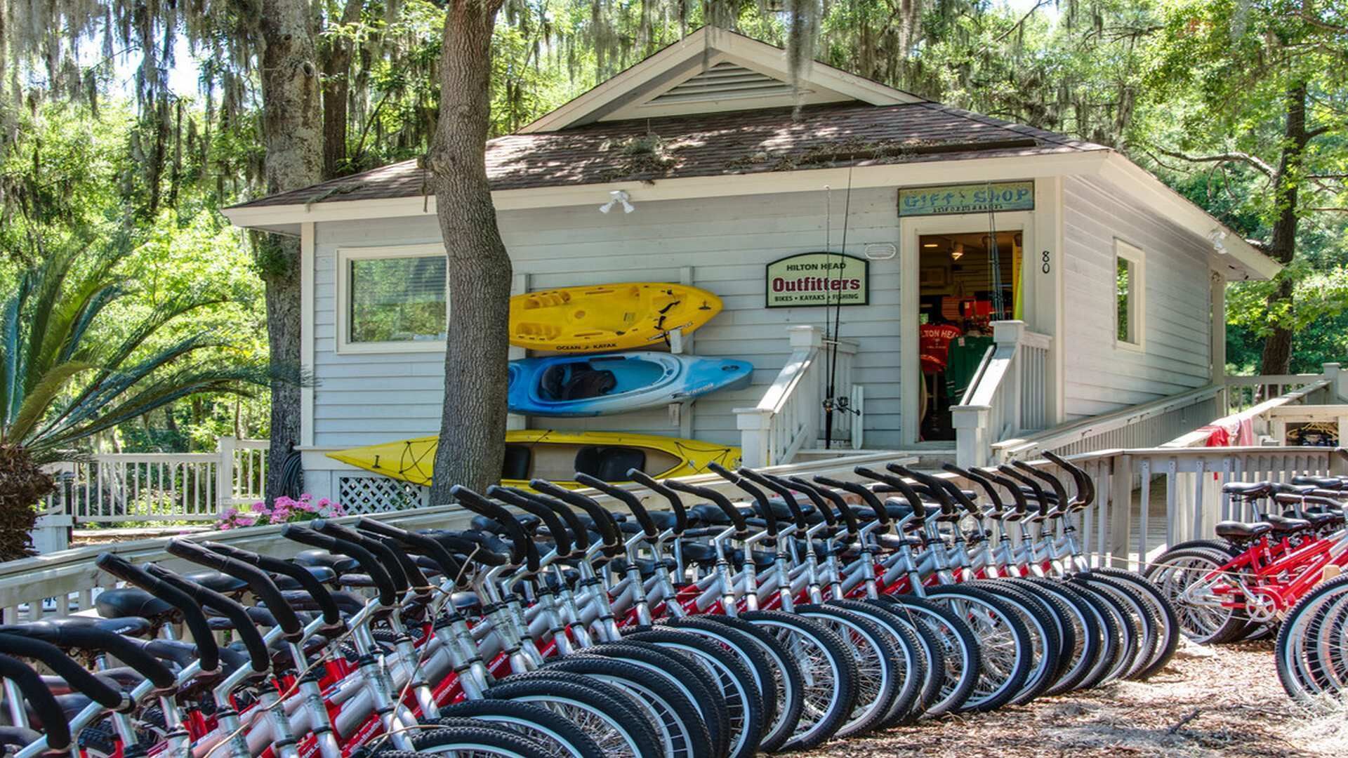 Una cabaña pequeña con un letrero que dice 'Hilton Head Outfitters' y kayaks guardados afuera.