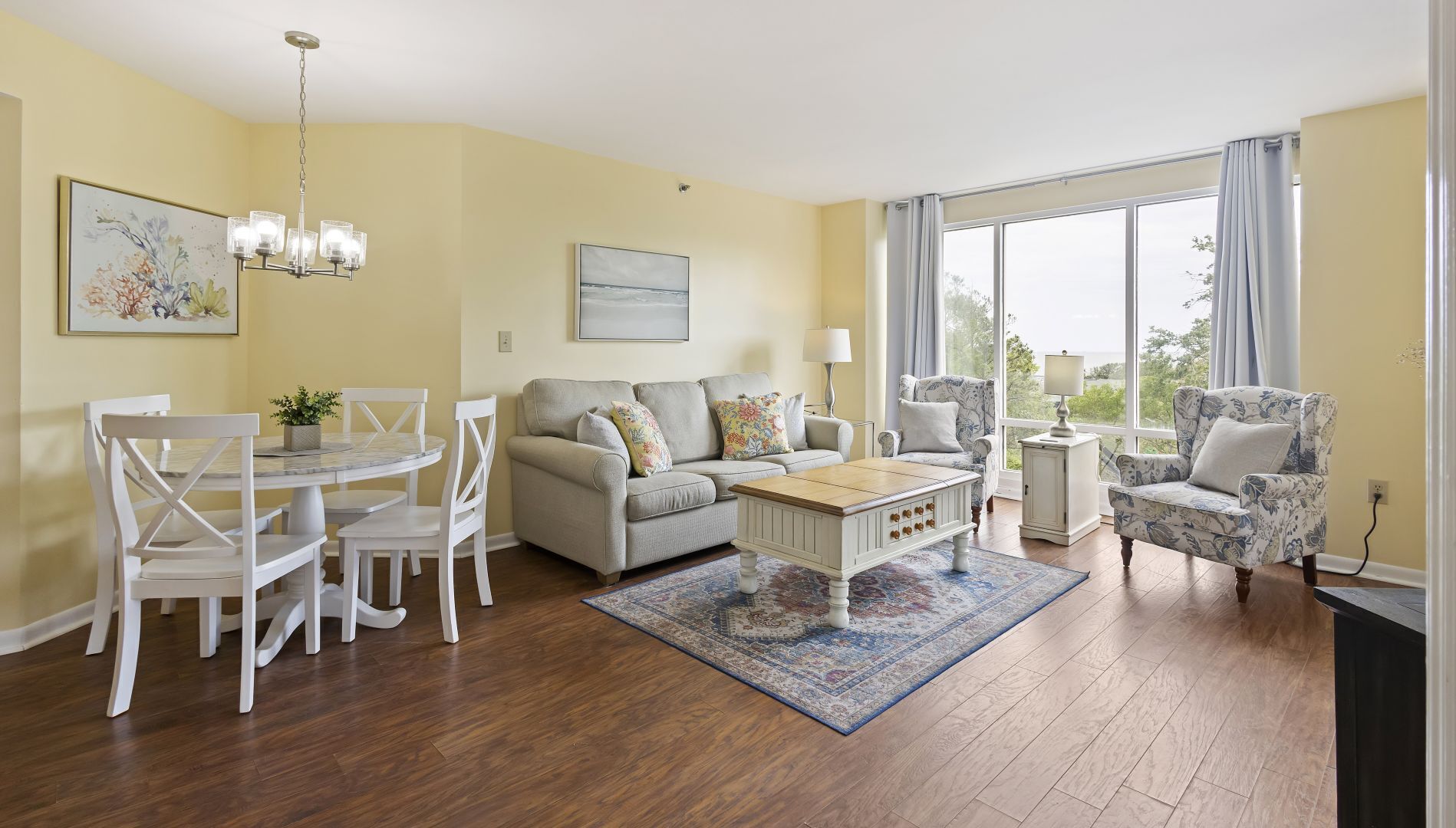 A living room with a dining area, a sofa, a coffee table, and a patterned rug.