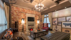 A cozy living room with a brick wall, leather sofa, and a fireplace.