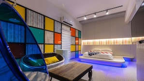 A modern room with a hanging chair, a bed with a unique headboard, and a colorful wall with a built-in shelf.