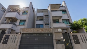 A multi-story building with a garage entrance, balconies, and a clear sky.