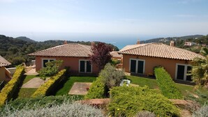 Un barrio residencial con casas de tejados de terracota, un jardín cuidado y vista al mar de fondo.