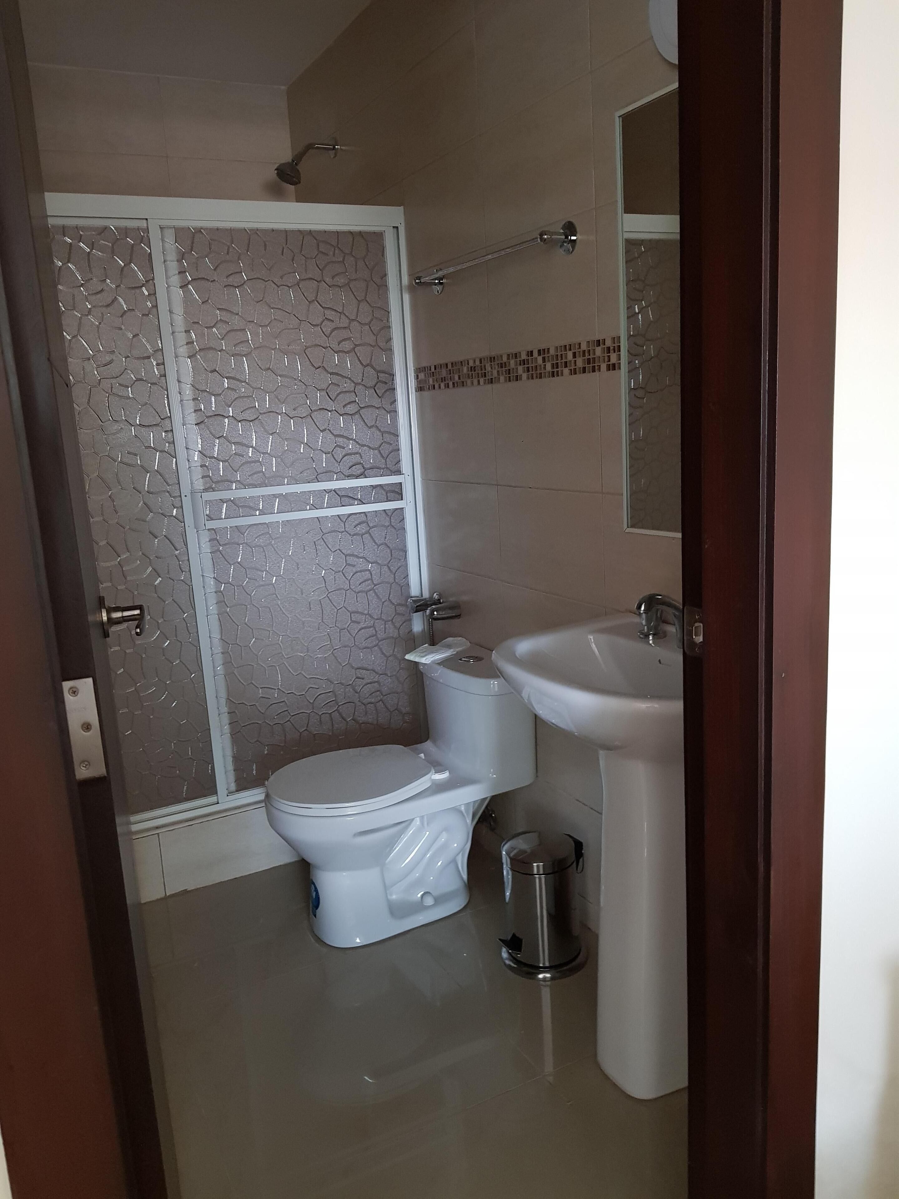 A bathroom with a toilet, bidet, sink, and a glass shower enclosure.