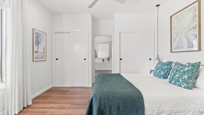 A bedroom with a bed, a nightstand, a mirror, and a door leading to another room.