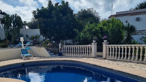 A swimming pool with a curved edge, surrounded by a low white fence, and a few lounge chairs. - quietly situated villa at 900 m from the beach (Benissa)