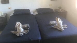 A hotel room with two beds, each with a towel on the bed. There is a nightstand with a lamp and a small plant on it. - quietly situated villa at 900 m from the beach (Benissa)