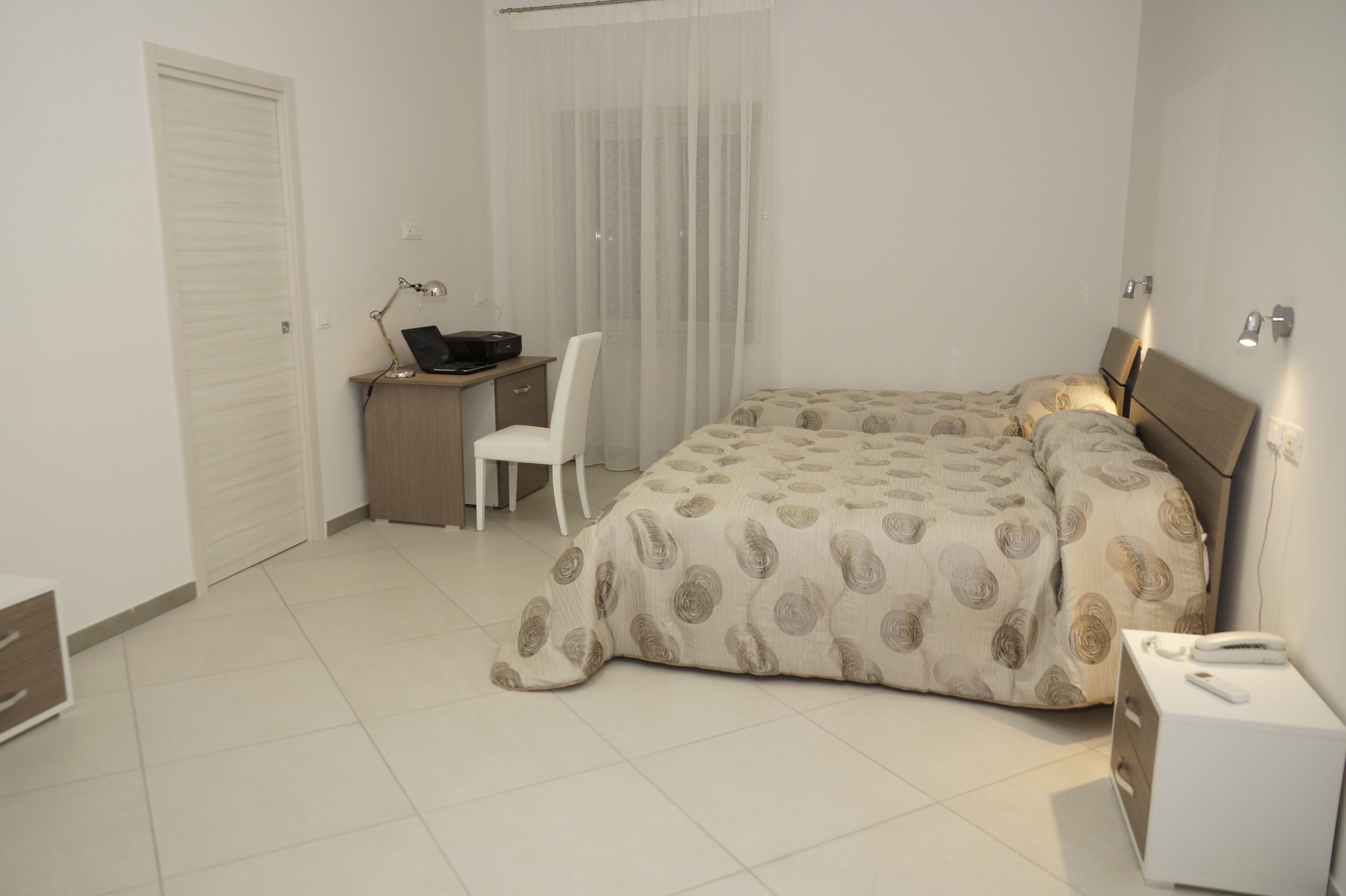 Une chambre à coucher comprenant un lit, un bureau avec une chaise, une table de chevet et une armoire.