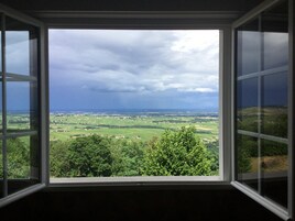 Una ventana con vista a un paisaje verde y un cielo nublado.