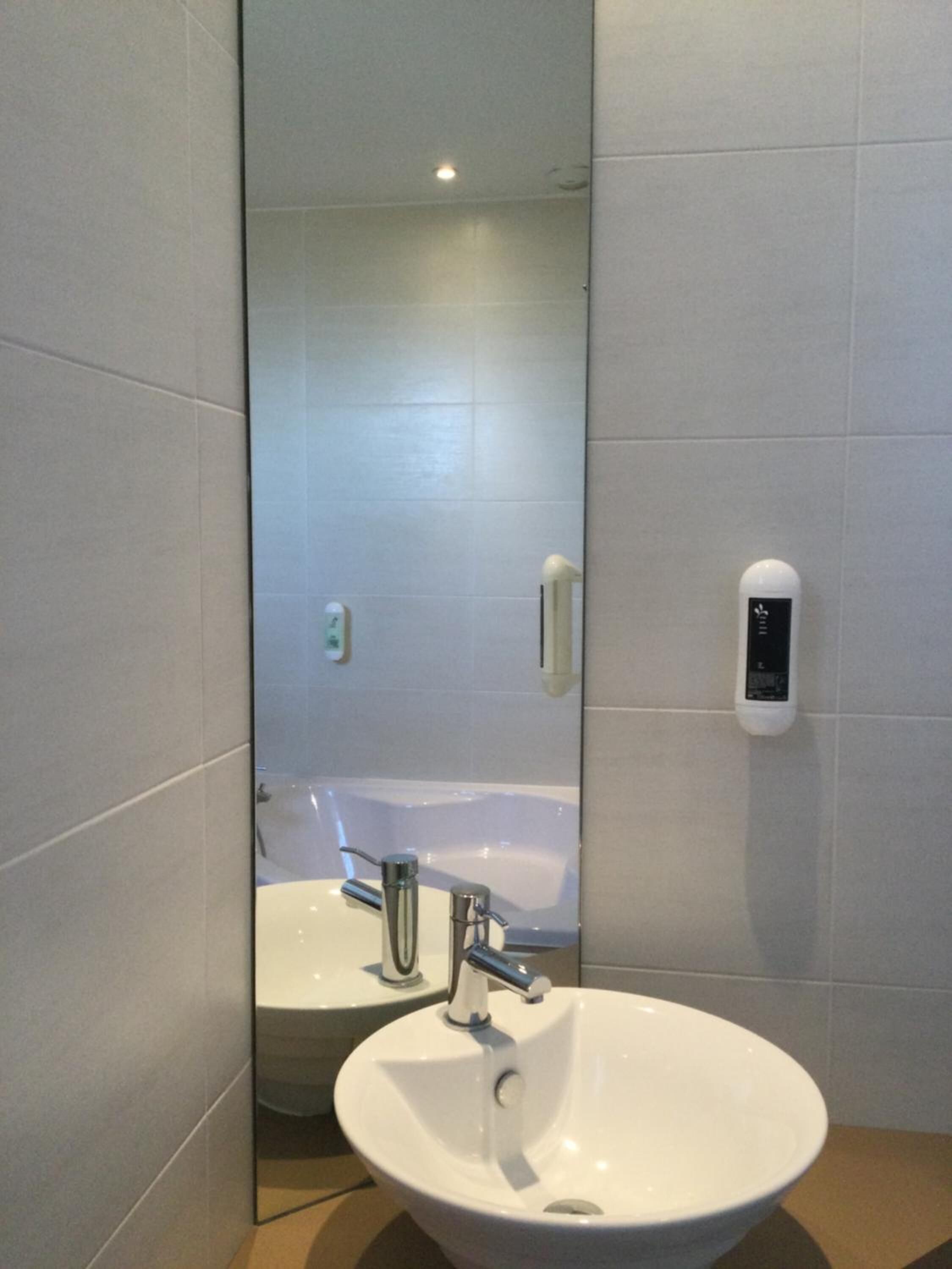 Et badeværelse med en hvid vask, et spejl og et hvidt toilet.
