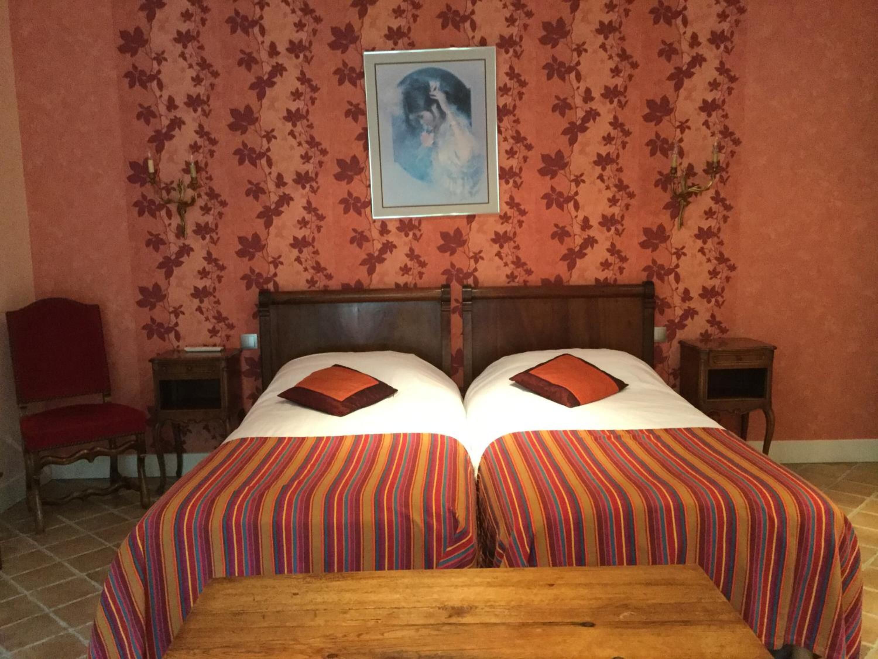 Een tweepersoonsbed met gestreept beddengoed, een houten hoofdbord en twee nachtkastjes met lampen.
