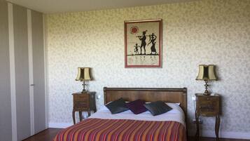 A bedroom with a striped bedspread, a wooden headboard, two bedside tables with lamps, and a wall-mounted picture.