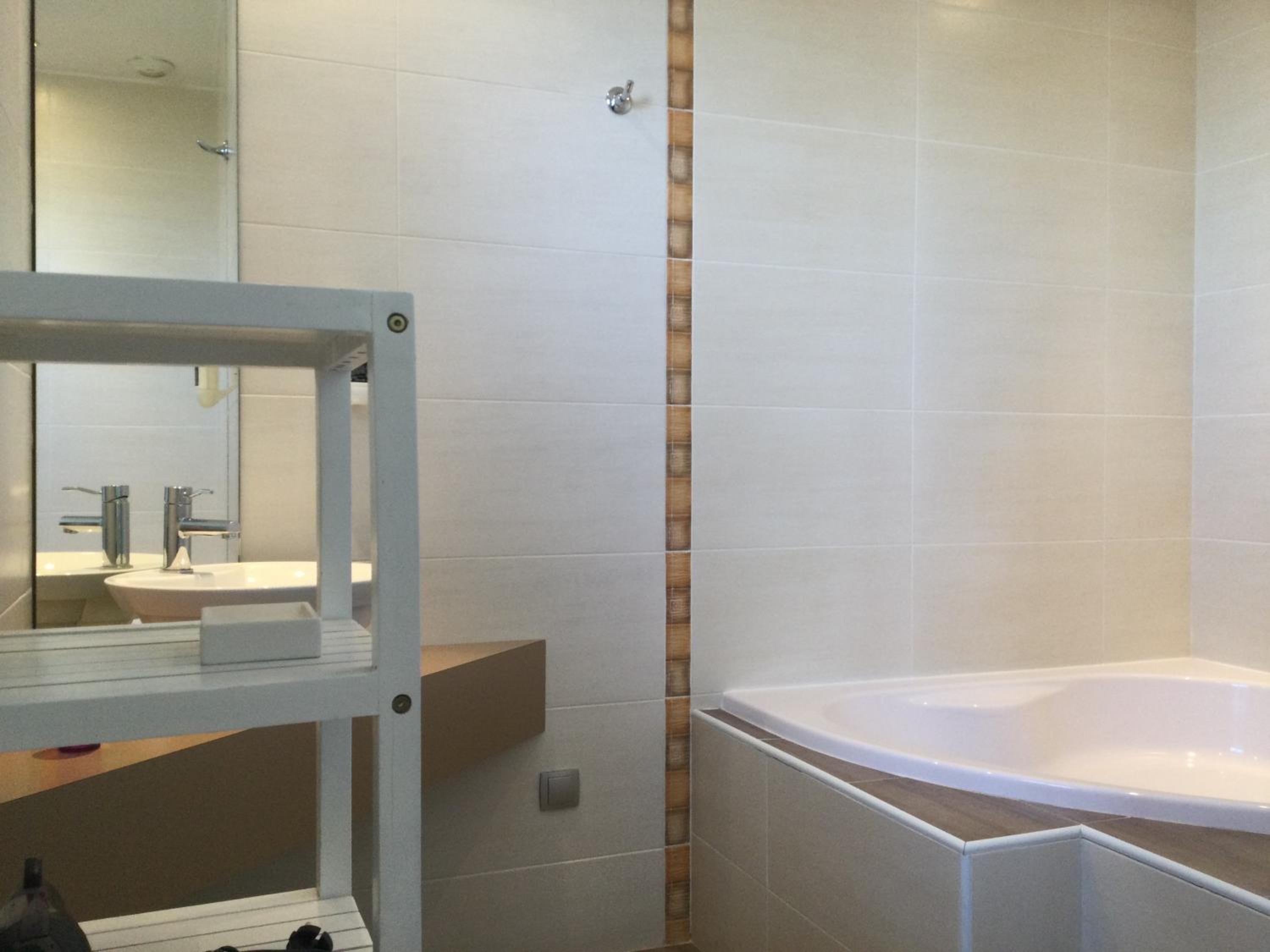 Un baño moderno con una bañera grande, un lavabo y un espejo.