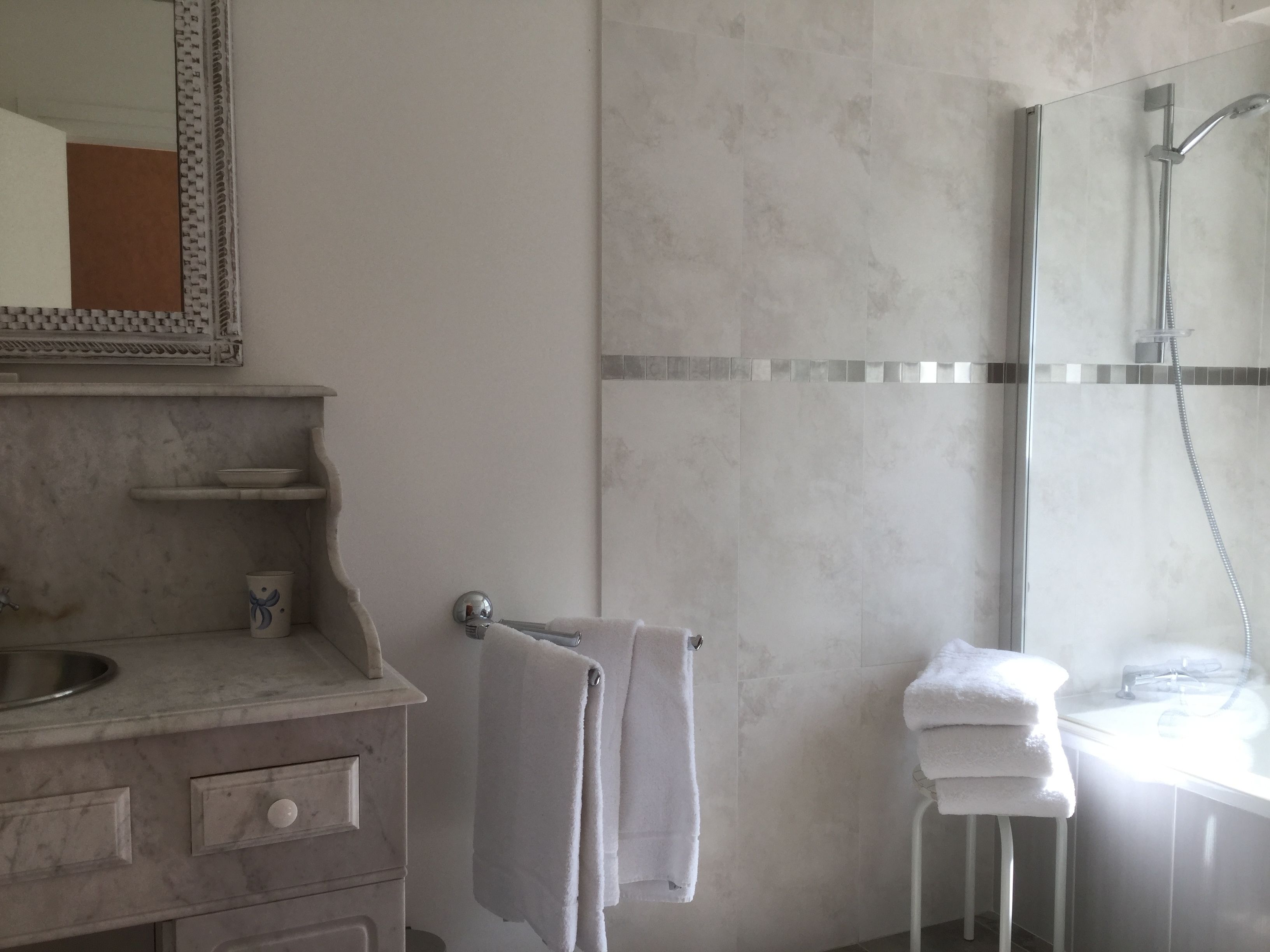 Un bagno moderno con un mobile lavabo in marmo, cabina doccia in vetro e un portasciugamani bianco.