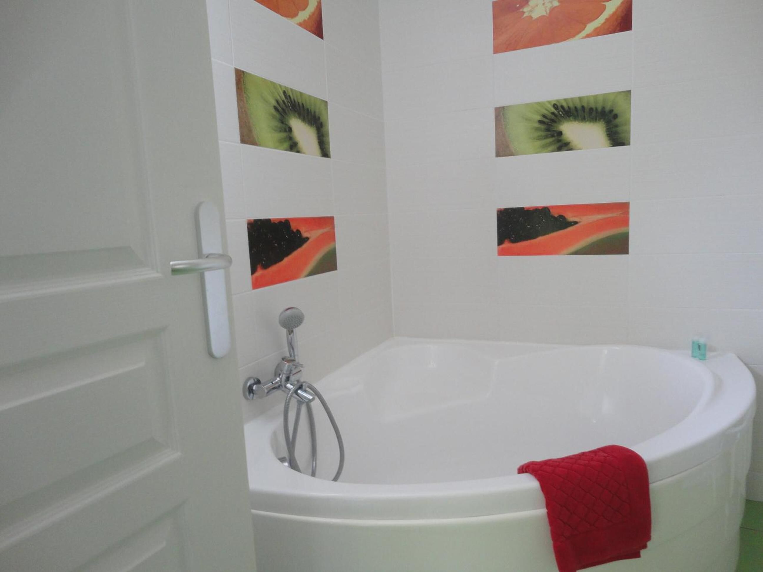 Een badkamer met een wit bad, een douche en een deur.