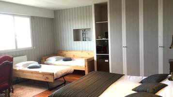 A bedroom with two single beds, a desk, a wardrobe, and a mirror.