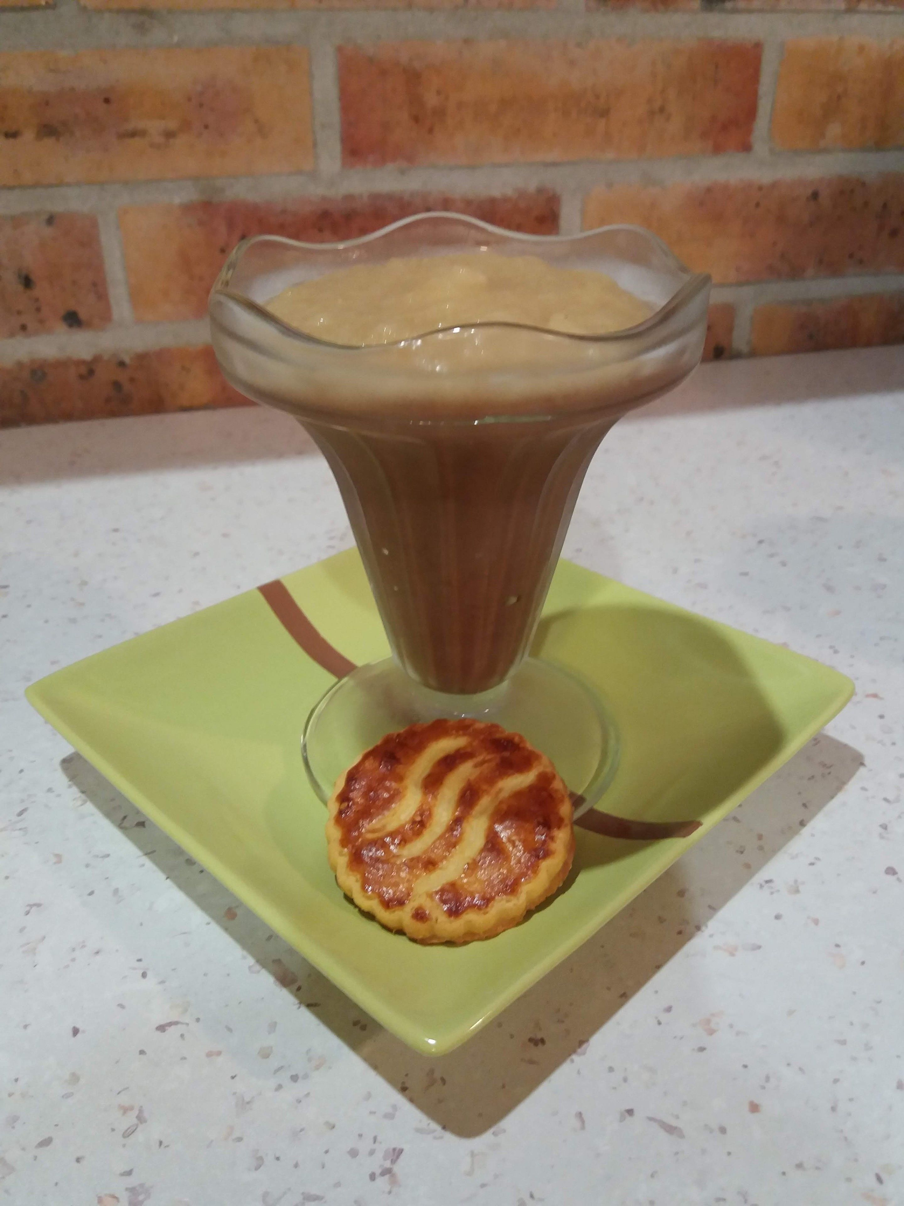 A glass of coffee on a green square plate with a pastry on a smaller plate beside it.