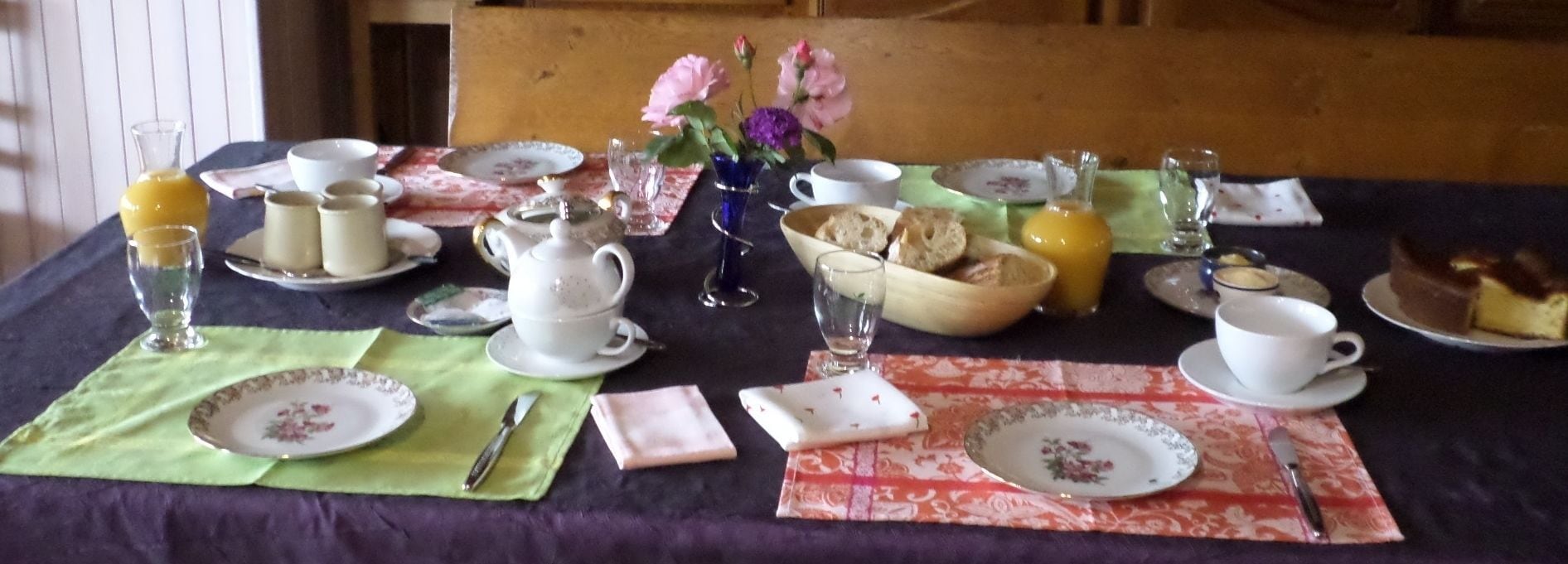A table set with tea cups, teapots, plates, and a variety of food items, suggesting a meal setup.