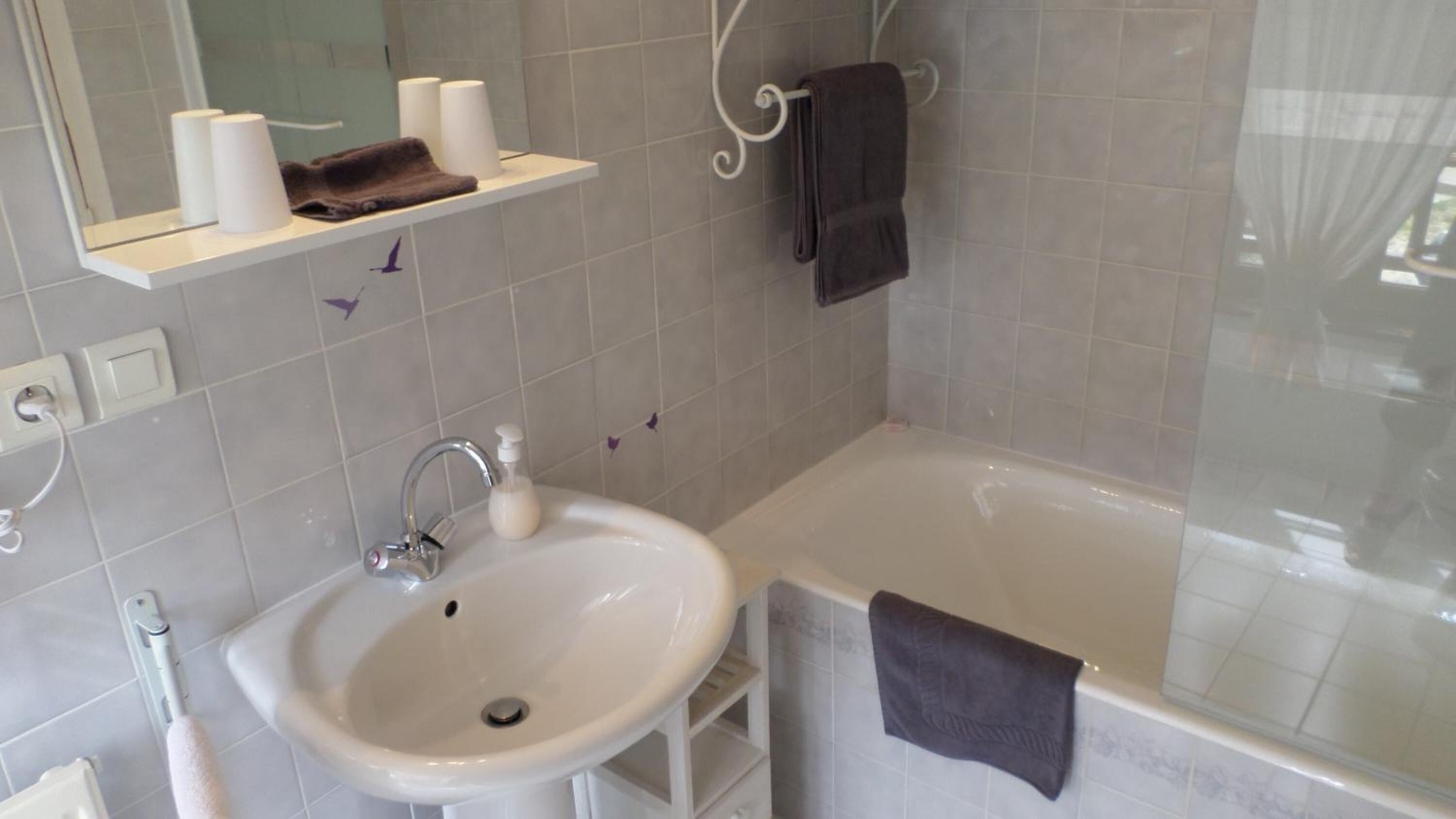 A bathroom with a sink, a mirror, a towel rack, and a bathtub.