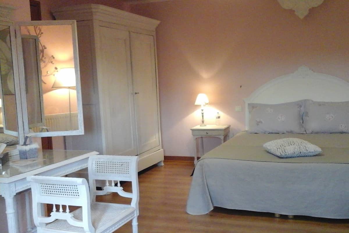 Un dormitorio con cama, mesita de noche, lámpara, armario y una silla.