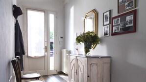 A hallway with a white door, a radiator, a cabinet, and a mirror on the wall.