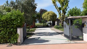 A gated driveway leading to a building with a gravel path and surrounding greenery.