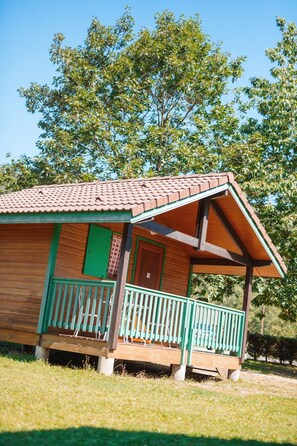 A wooden cabin with a tiled roof, a porch with green railings, and a door with a green window. - Base de Loisirs du Lac de la Moselotte (Saulxures-sur-Moselotte)