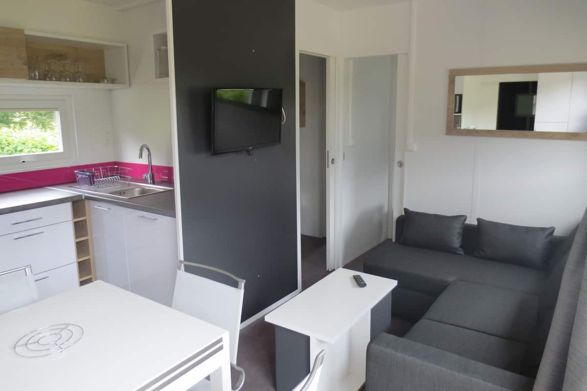 Una cocina moderna con un lavamanos, una mesa de comedor y un televisor montado en la pared.