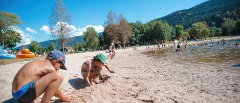 A sandy beach with people playing and swimming in the water.