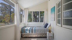 A bedroom with a bed, a nightstand, a window, and a view of trees. - Evans Above - 1-5 Wattle Street (EVANS HEAD)