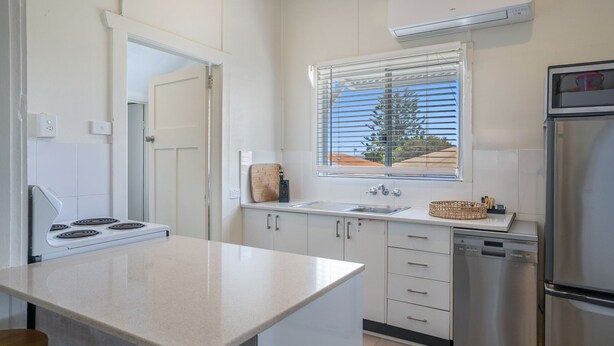 A compact kitchen with white cabinets, a stove, a sink, and a refrigerator. - Evans Above - 1-5 Wattle Street (EVANS HEAD)
