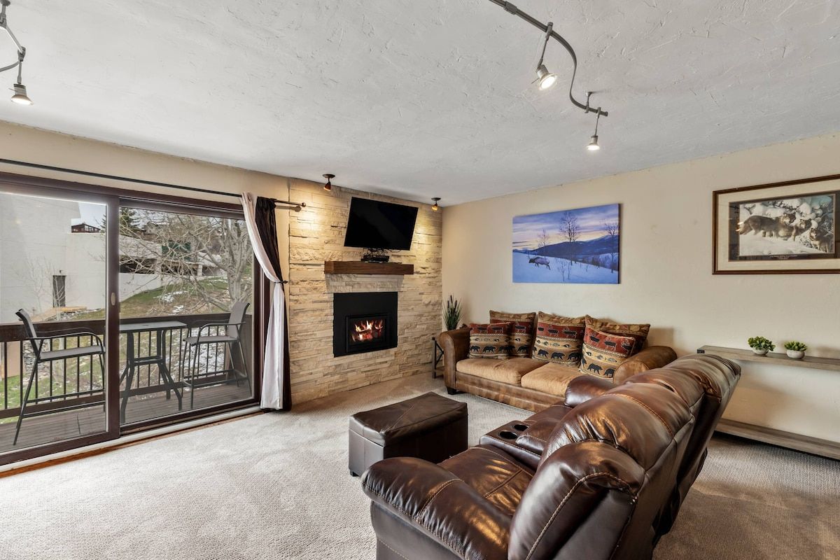 Relax in this warm and inviting living room, featuring a stone fireplace, mounted TV, and plenty of cozy seating—perfect for unwinding.