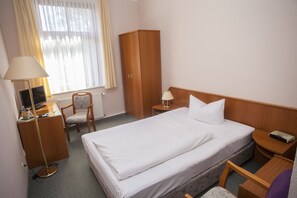 A hotel room with a bed, desk, chair, wardrobe, and a window with curtains. - Hotel am Kellerberg (Trockenborn-Wolfersdorf)