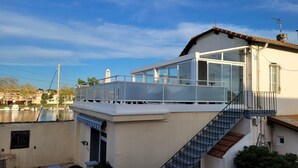 Een modern gebouw met een glazen balkon, een trap en uitzicht op een gracht.