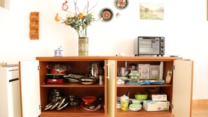 A kitchen with open cabinets displaying kitchenware, a vase with flowers, and a microwave. - LA CASA DEI PARGOLI, apartment ideal for pleasant holidays in Matera (Matera)