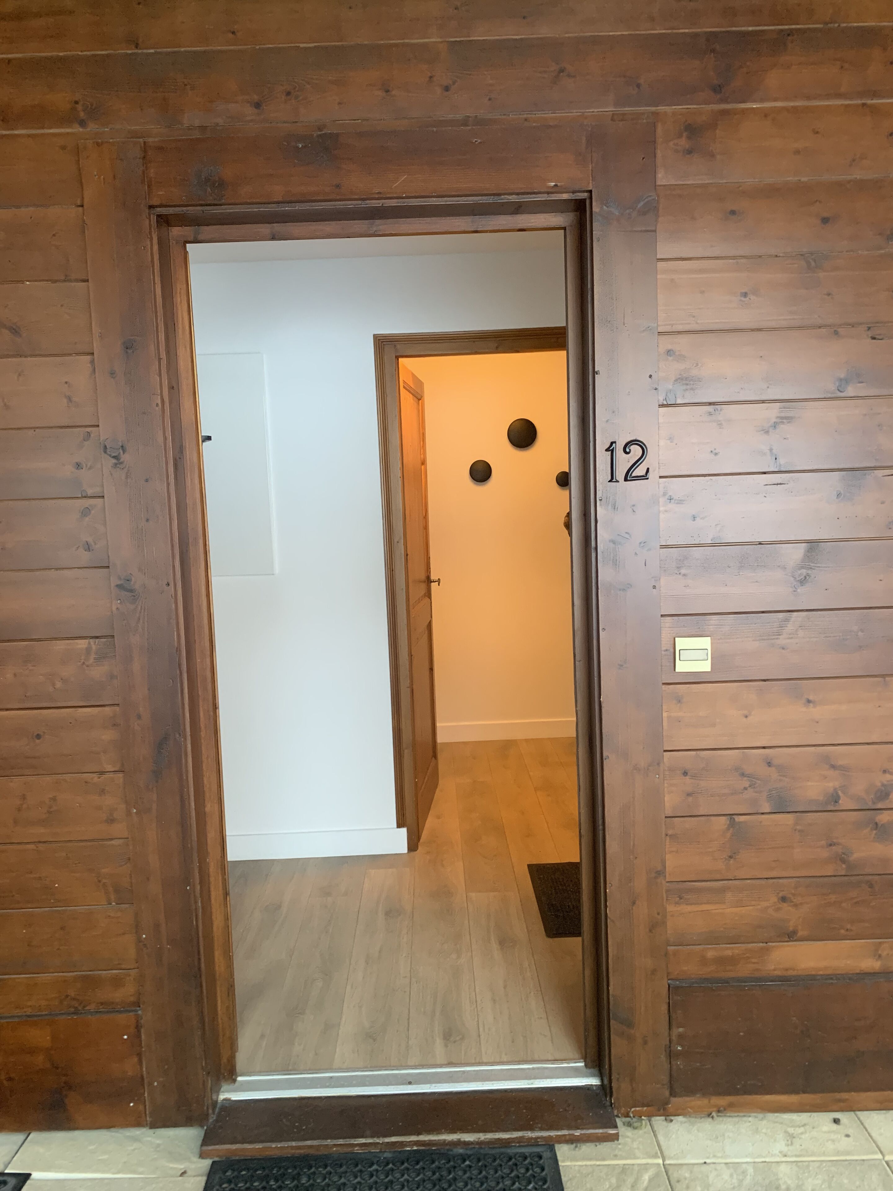 Una puerta de madera con el número 12 en la pared de al lado.