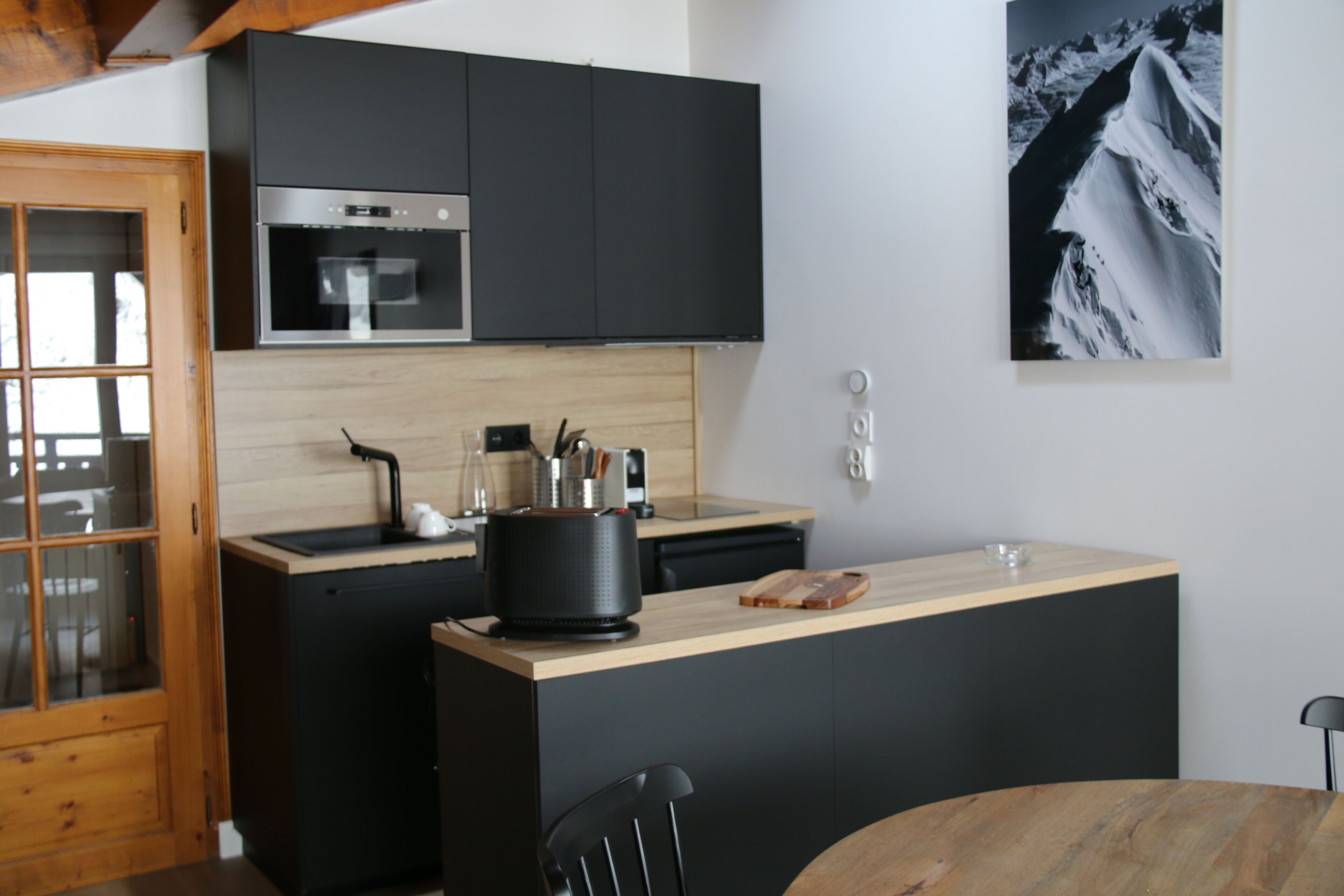 Une cuisine moderne avec des meubles de couleur noire, un plan de travail en bois et une cuisinière noire.