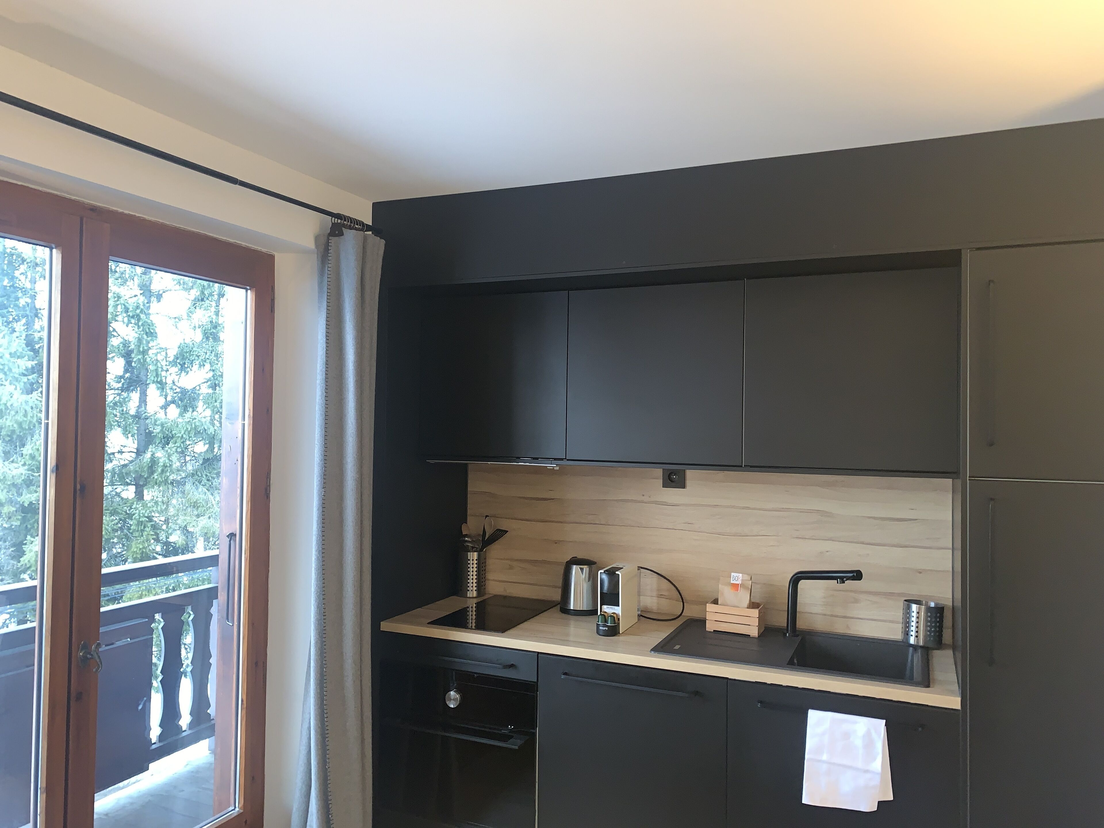 A modern kitchen with dark cabinets, a wooden countertop, and a built-in oven.