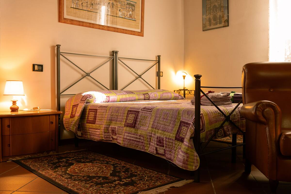 A bedroom with a bed, a nightstand, a chair, and a rug.