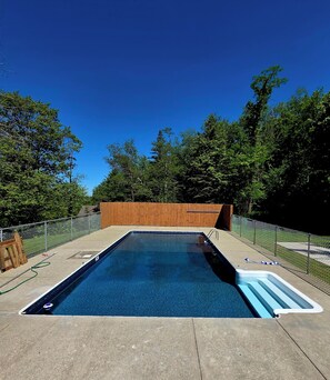 A rectangular swimming pool with a wooden fence and a wooden deck surrounding it.