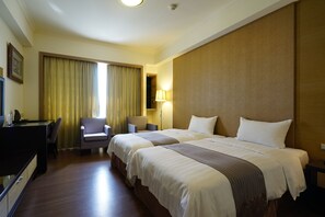 A hotel room with two beds, a desk, a chair, and a lamp. - Penghu Haiyue Hotel (Magong)