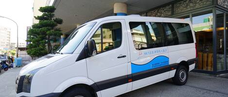 Een witte bestelwagen geparkeerd voor een gebouw met een blauw-wit ontwerp.