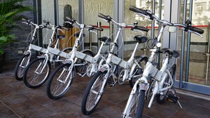 Reihenweise weiße Fahrräder vor einem Gebäude mit großen Fenstern.