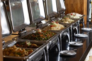 Een buffet met diverse gerechten, waaronder rijst, groenten en vleesgerechten.
