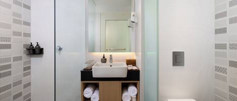 A modern bathroom with a glass shower enclosure, a white sink with a black countertop, and a toilet.