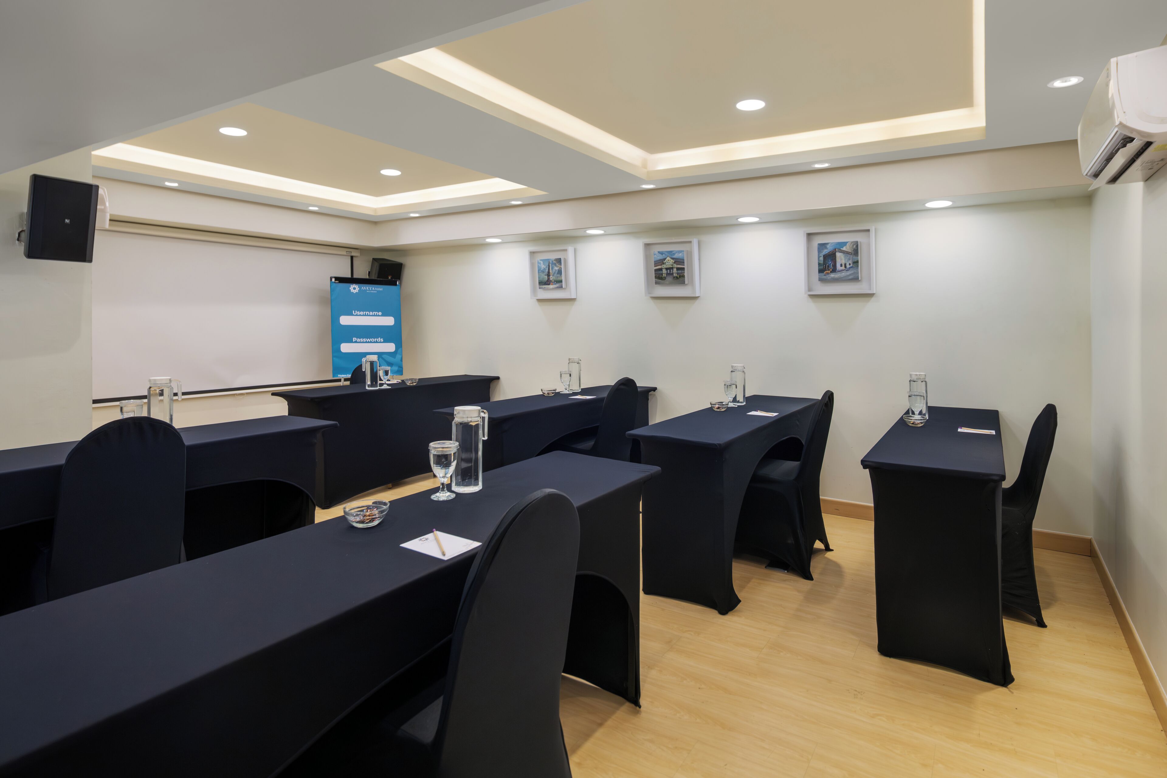 A conference room with tables, chairs, and a presentation screen.