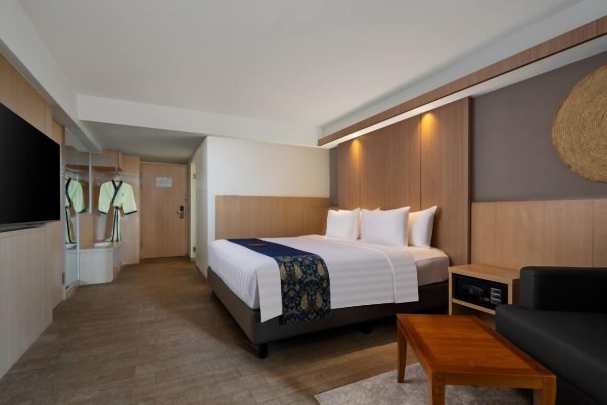 Ein Hotelzimmer mit Bett, einem Nachttisch aus Holz, einer schwarzen Couch, einem Holztisch und einem Fernseher.