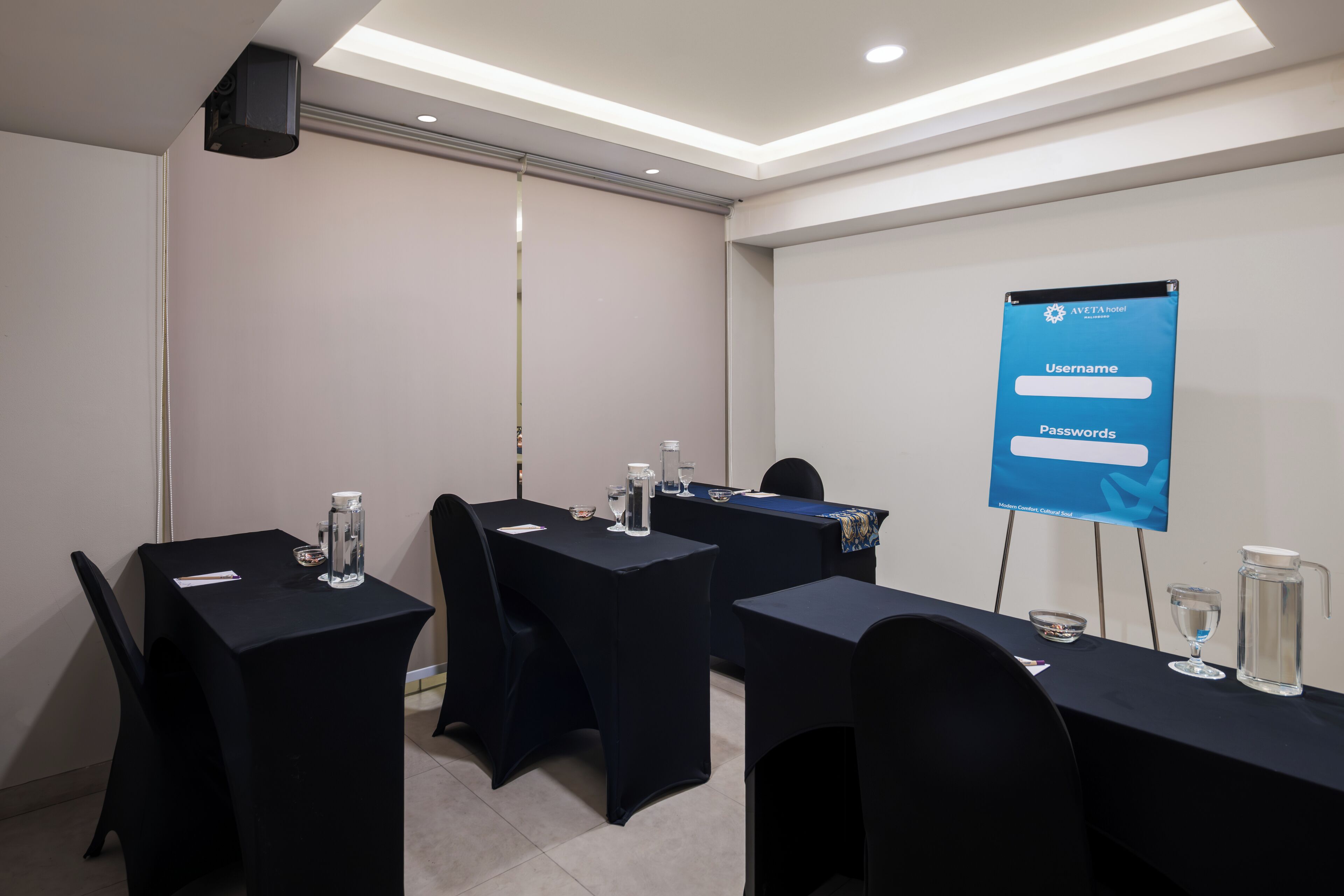A conference room with tables, chairs, and a banner displaying login credentials.